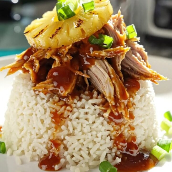 A close-up of shredded Huli Huli chicken in a turquoise ceramic slow cooker with steam rising.