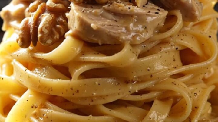 A close-up of shredded chicken in a creamy Gorgonzola sauce with pears and walnuts over tagliatelle.