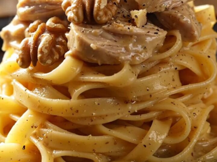 A close-up of shredded chicken in a creamy Gorgonzola sauce with pears and walnuts over tagliatelle.
