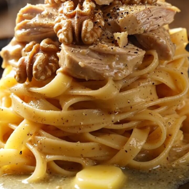 A close-up of shredded chicken in a creamy Gorgonzola sauce with pears and walnuts over tagliatelle.