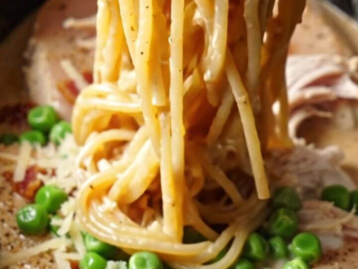 A steaming Crockpot filled with creamy shredded chicken and carbonara sauce.