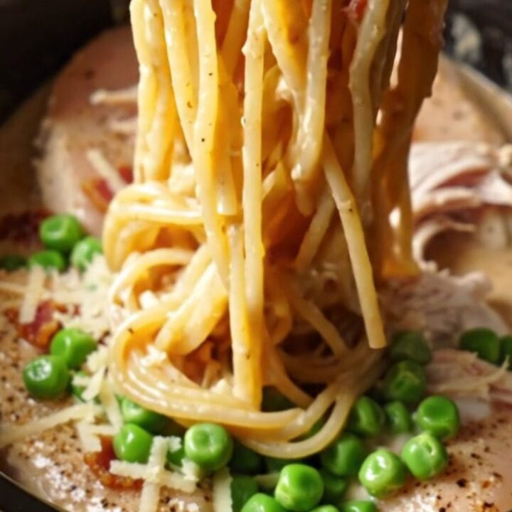 A steaming Crockpot filled with creamy shredded chicken and carbonara sauce.