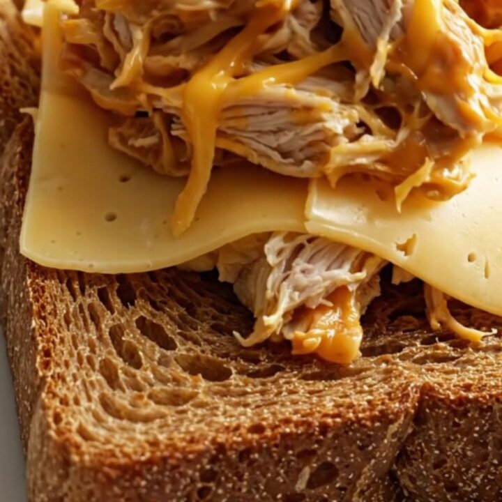Close up of shredded creamy Reuben chicken piled on toasted rye bread.