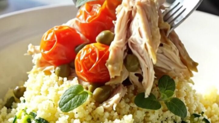 A close-up of tender shredded chicken with artichoke hearts and cherry tomatoes in a light wine sauce.