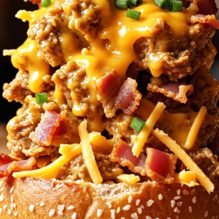 A close-up of shredded chicken in a creamy beer cheese sauce with crispy bacon, served on a toasted pretzel bun.