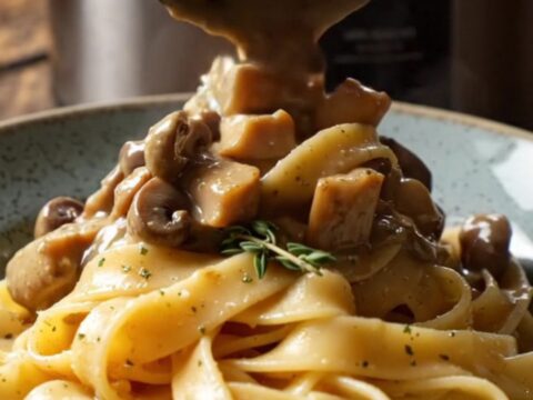 A bowl of shredded chicken in a creamy mushroom and truffle sauce served over pappardelle pasta.