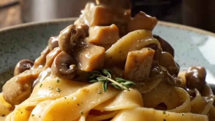 A bowl of shredded chicken in a creamy mushroom and truffle sauce served over pappardelle pasta.
