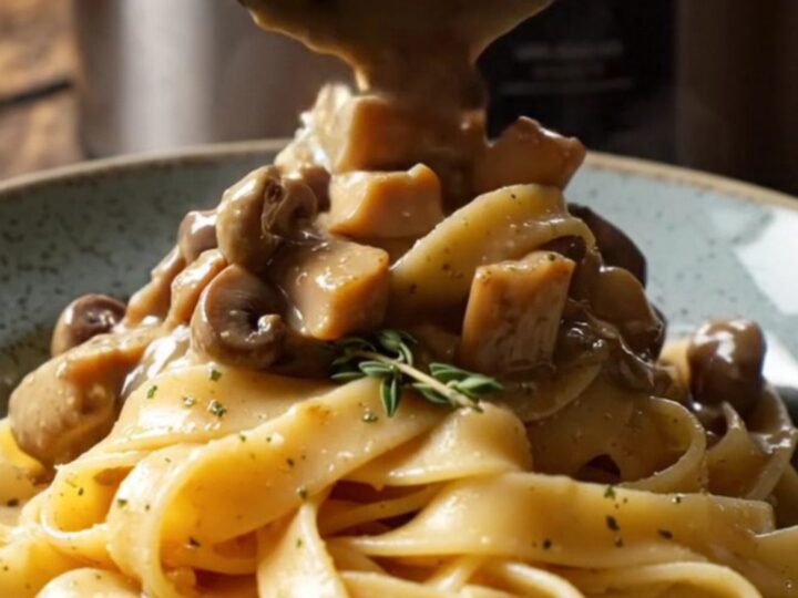 A bowl of shredded chicken in a creamy mushroom and truffle sauce served over pappardelle pasta.