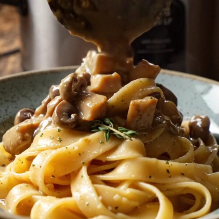 A bowl of shredded chicken in a creamy mushroom and truffle sauce served over pappardelle pasta.