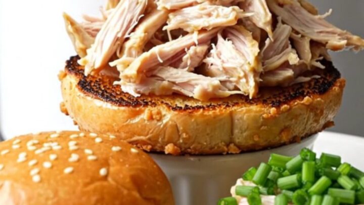 A ceramic slow cooker filled with creamy, shredded everything bagel crack chicken topped with fresh chives.