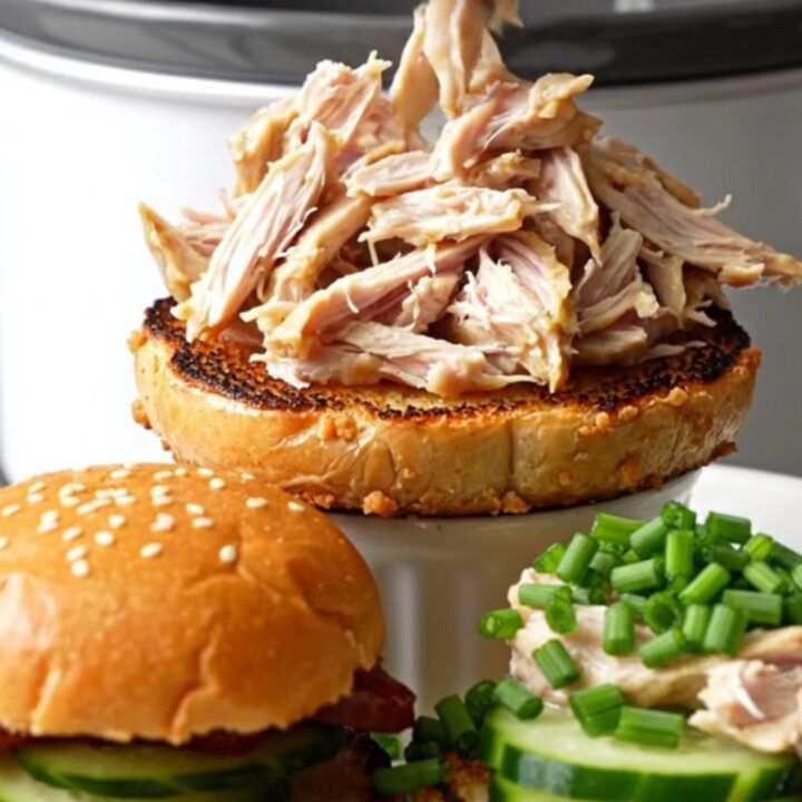 A ceramic slow cooker filled with creamy, shredded everything bagel crack chicken topped with fresh chives.
