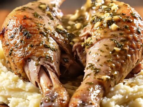 Two roasted turkey drumsticks glistening with herb butter and wine jus in a slow cooker.