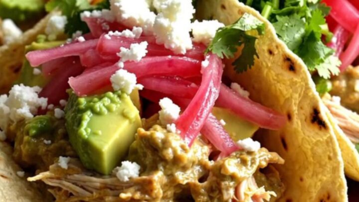 A close-up of shredded chicken in a creamy lime sauce inside a slow cooker with fresh cilantro.