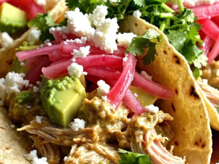 A close-up of shredded chicken in a creamy lime sauce inside a slow cooker with fresh cilantro.