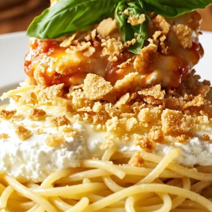A close-up of tender chicken breast in a slow cooker topped with melted ricotta, mozzarella, and marinara sauce.