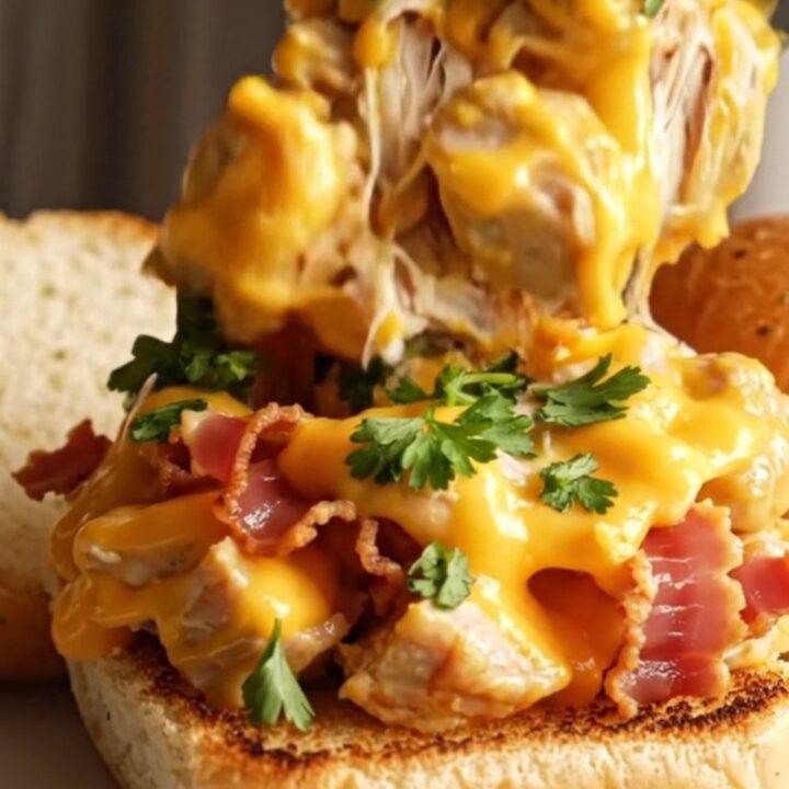 A close-up of a slow cooker filled with shredded chicken in a thick, bubbly five-cheese sauce with crispy pancetta.