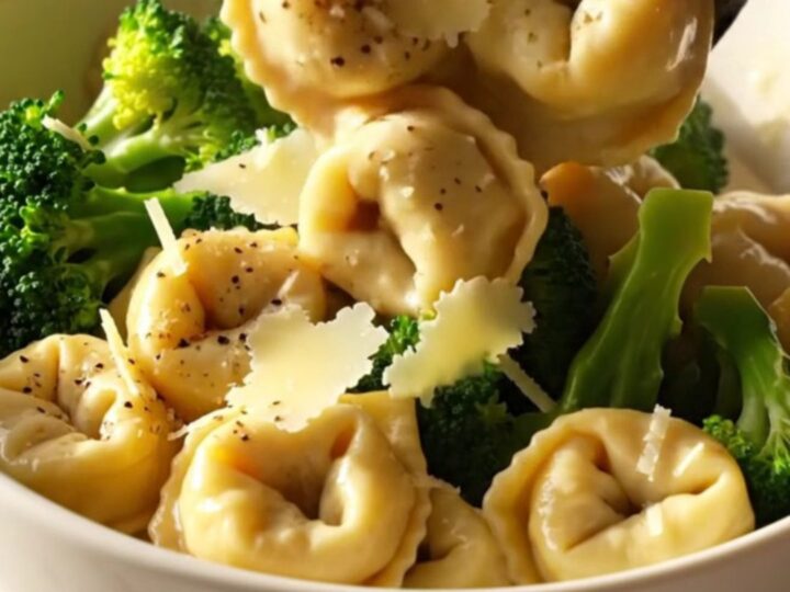 A steaming bowl of creamy chicken and broccoli tortellini topped with parmesan curls.