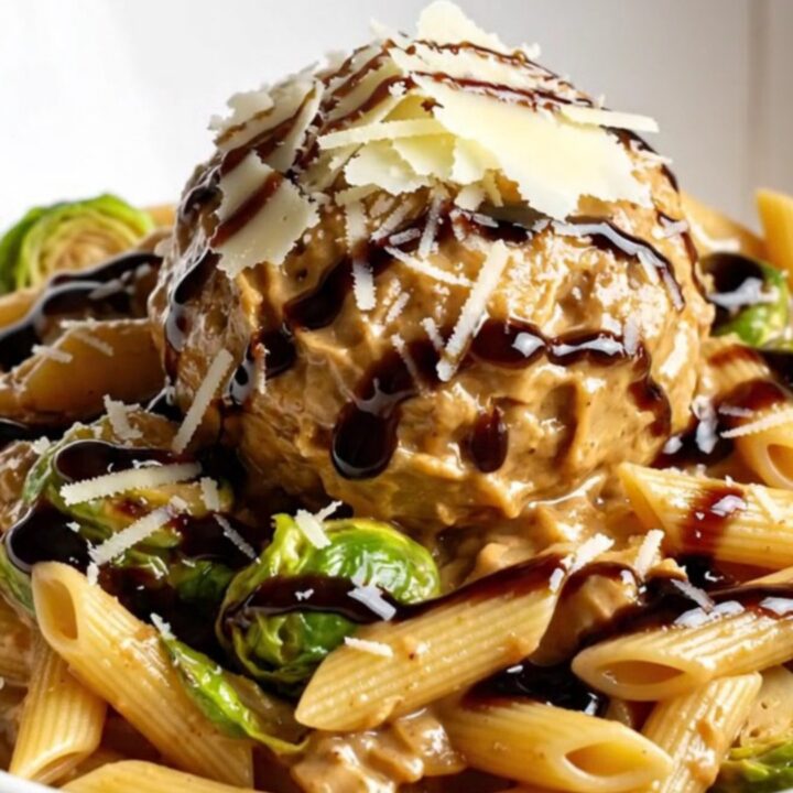 A close-up of creamy penne pasta with bacon and Brussels sprouts in a slow cooker.