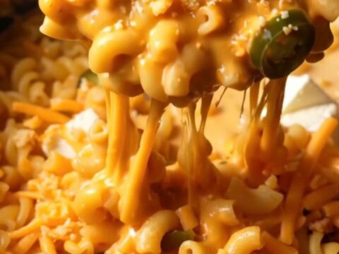 A close-up shot of creamy jalapeno popper mac and cheese in a crockpot, topped with crispy bacon and charred jalapenos.