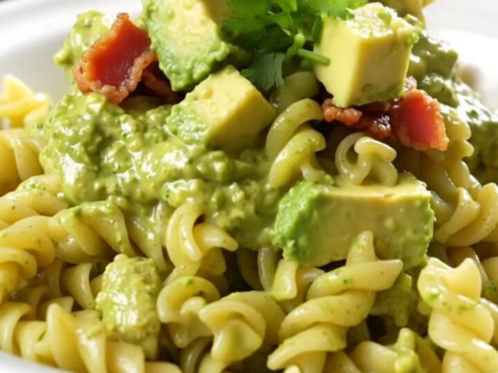 A creamy bowl of chicken bacon ranch pasta garnished with fresh cilantro and avocado slices.