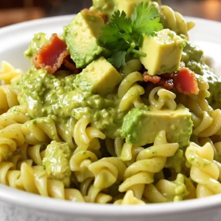A creamy bowl of chicken bacon ranch pasta garnished with fresh cilantro and avocado slices.