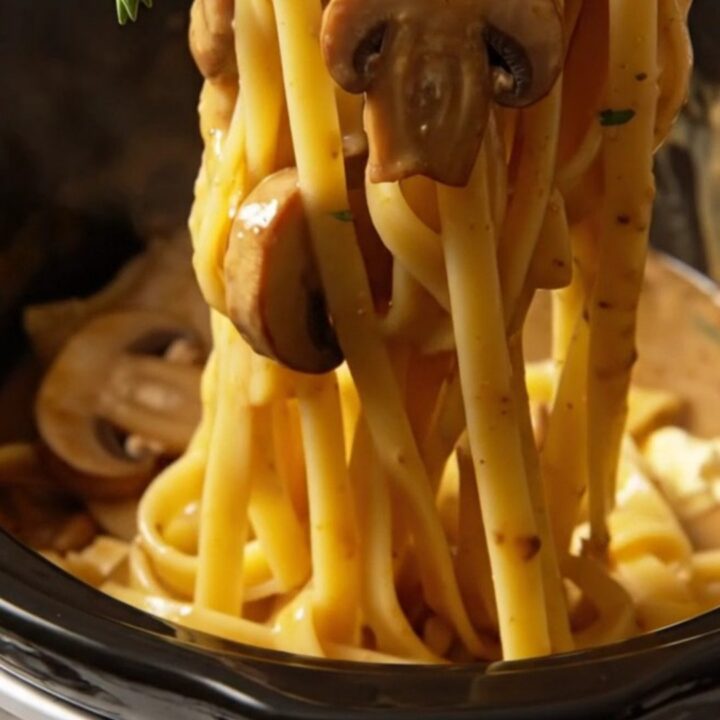 A close-up of creamy chicken Marsala fettuccine with mushrooms in a rustic bowl.
