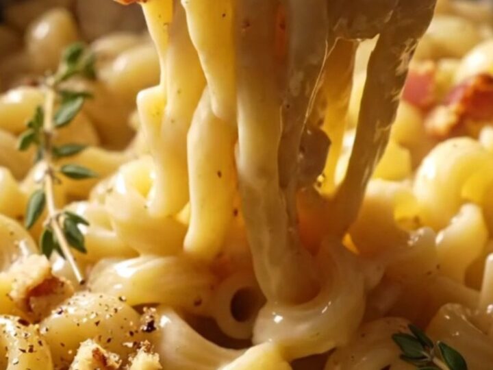 A close-up of cavatappi pasta coated in a creamy brie sauce, topped with toasted walnuts and black pepper.