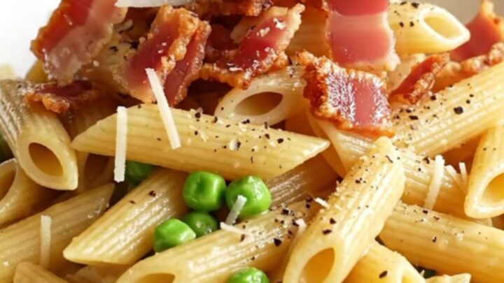 A steaming bowl of creamy Boursin chicken carbonara topped with crispy pancetta and black pepper.