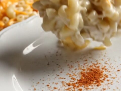 A close-up of creamy, golden-edged Southern mac and cheese being scooped from a red Crockpot.