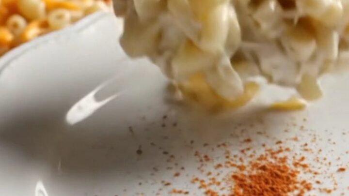 A close-up of creamy, golden-edged Southern mac and cheese being scooped from a red Crockpot.