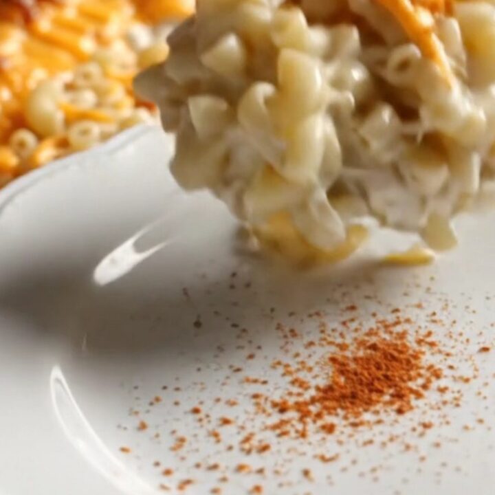 A close-up of creamy, golden-edged Southern mac and cheese being scooped from a red Crockpot.