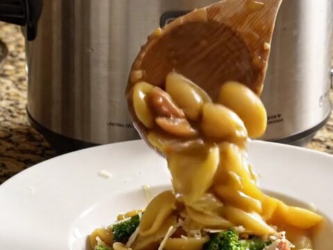 A close-up of a bowl filled with orecchiette pasta, spicy sausage, and broccoli rabe in a glossy garlic broth.