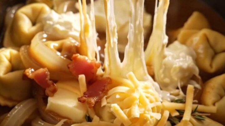 A steaming bowl of French onion tortellini topped with melted Gruyere and crispy bacon bits.