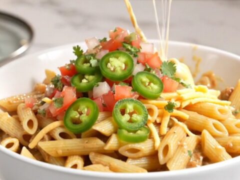 A close-up of creamy steak fajita pasta in a charcoal slow cooker with visible tender beef and peppers.