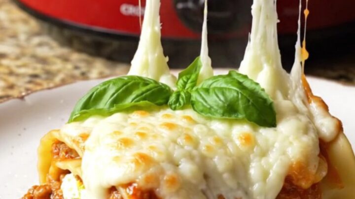 A close-up shot of spinach and ricotta lasagna roll-ups in a Crockpot with melted mozzarella.