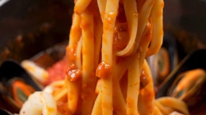 A close-up of seafood Fra Diavolo pasta with shrimp, mussels, and calamari in a spicy red sauce.