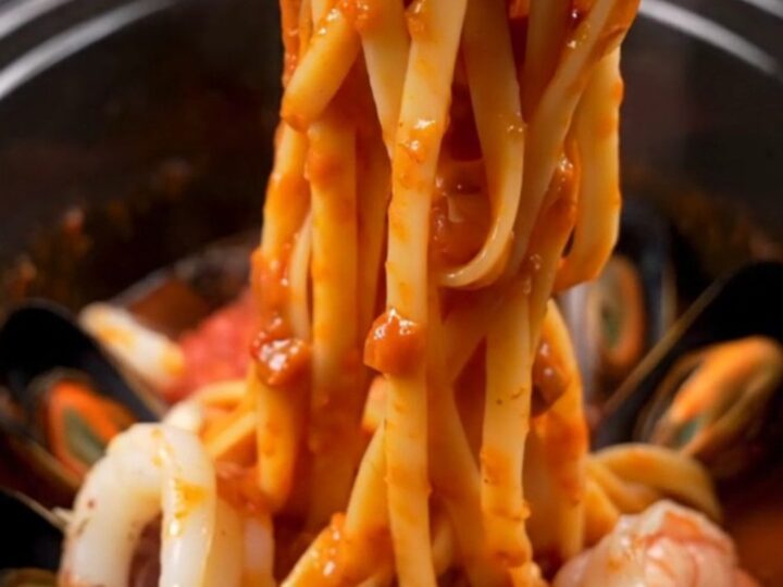 A close-up of seafood Fra Diavolo pasta with shrimp, mussels, and calamari in a spicy red sauce.