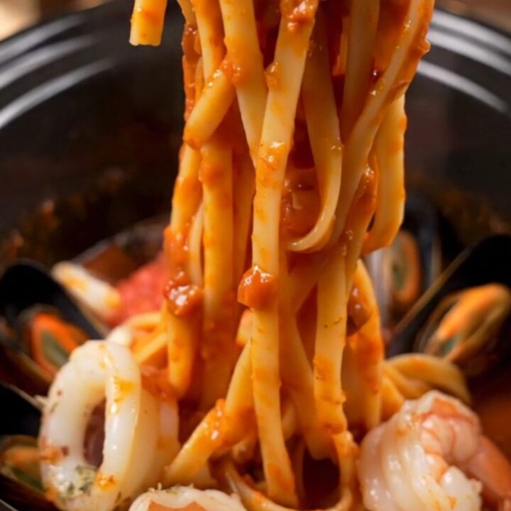 A close-up of seafood Fra Diavolo pasta with shrimp, mussels, and calamari in a spicy red sauce.