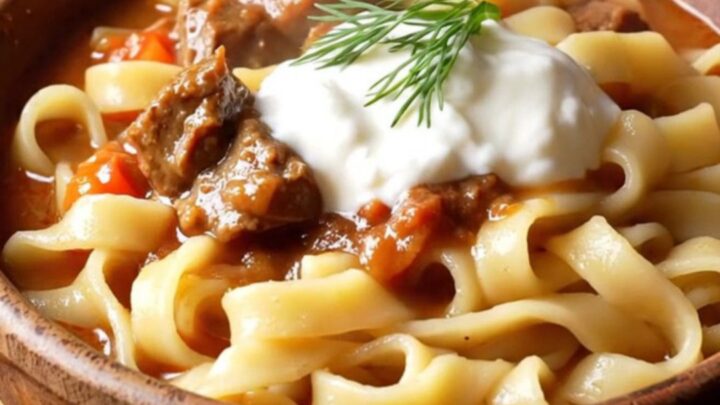 A warm bowl of Hungarian beef goulash with tender beef chunks and peppers over buttered egg noodles.
