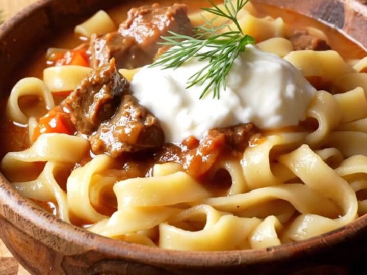 A warm bowl of Hungarian beef goulash with tender beef chunks and peppers over buttered egg noodles.