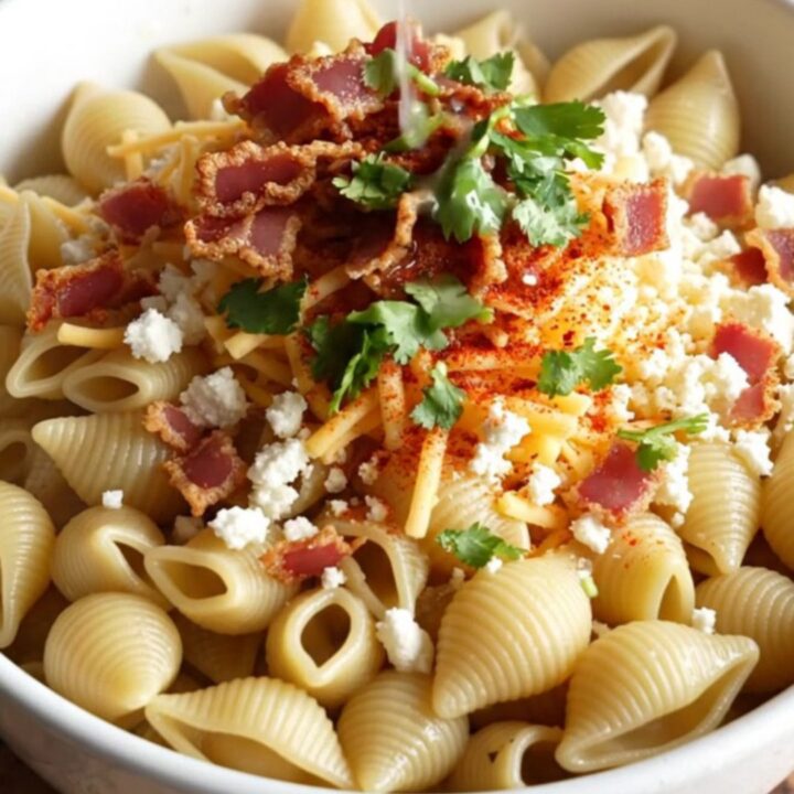 A steaming bowl of creamy Mexican street corn pasta topped with crispy bacon, fresh cilantro, and a dusting of Tajín.