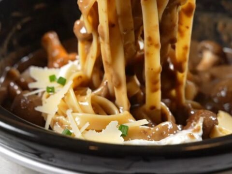 A close-up of glossy tagliatelle pasta coated in a rich, creamy mushroom and truffle sauce.