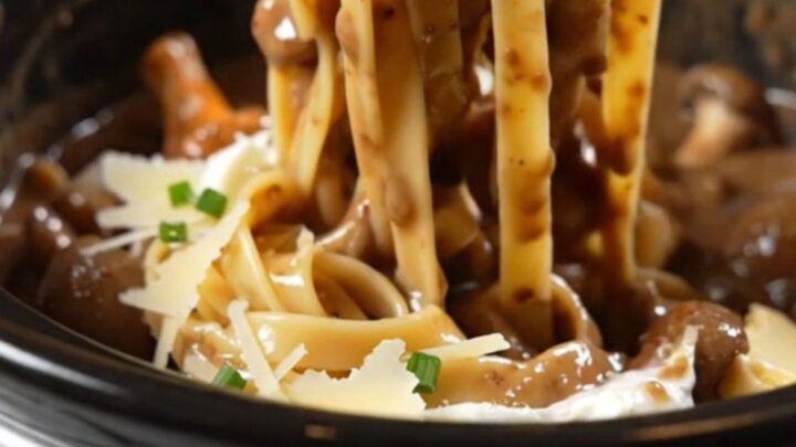 A close-up of glossy tagliatelle pasta coated in a rich, creamy mushroom and truffle sauce.