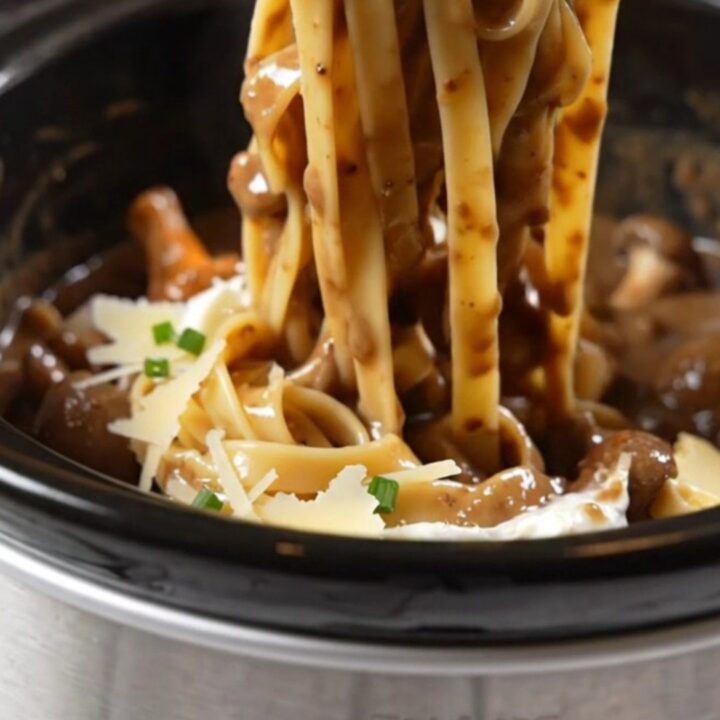 A close-up of glossy tagliatelle pasta coated in a rich, creamy mushroom and truffle sauce.