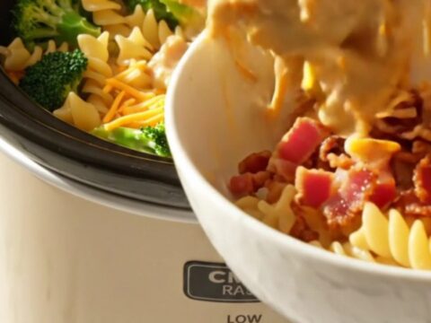 A close-up view of the creamy crockpot chicken, broccoli, and rotini pasta topped with crispy bacon bits.
