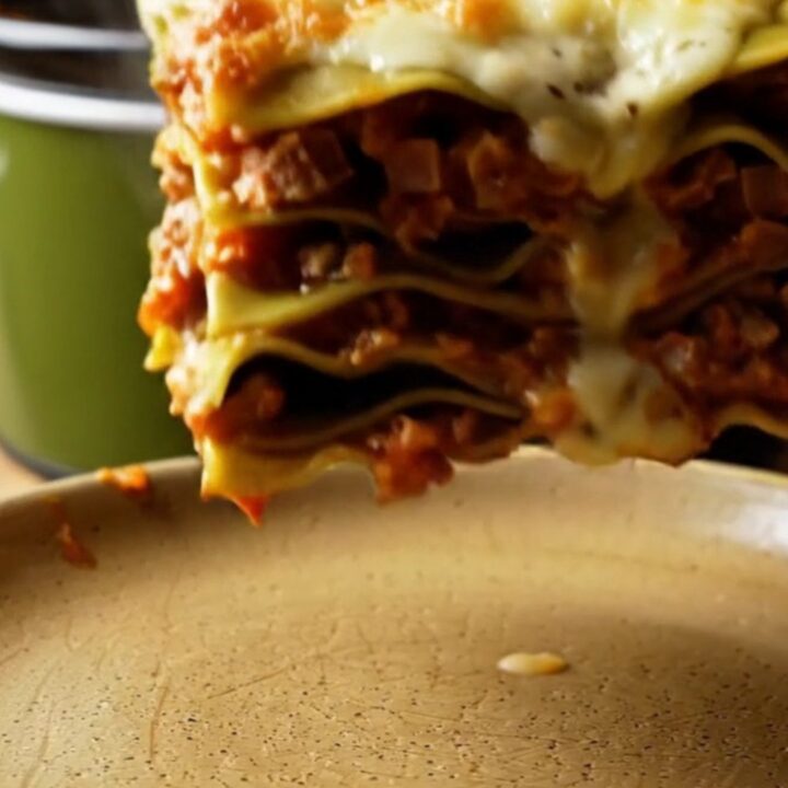 A close-up of a square of Lasagna Bolognese with visible layers of meat sauce, spinach pasta, and melted cheese.