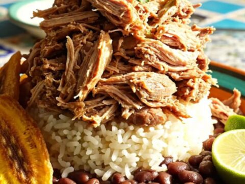 A close-up of tender shredded Cuban mojo pork glistening in a ceramic slow cooker with vibrant herb-infused juices.