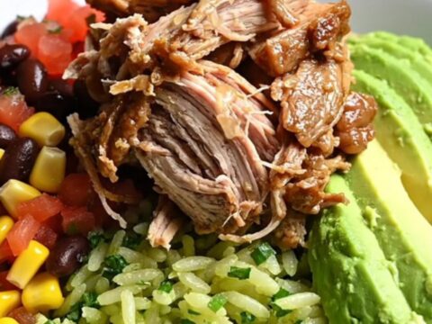 A close-up of a burrito bowl featuring smoky shredded chipotle honey pork, black beans, corn, and avocado.