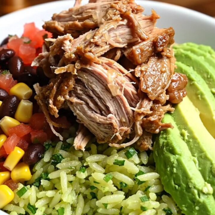 A close-up of a burrito bowl featuring smoky shredded chipotle honey pork, black beans, corn, and avocado.