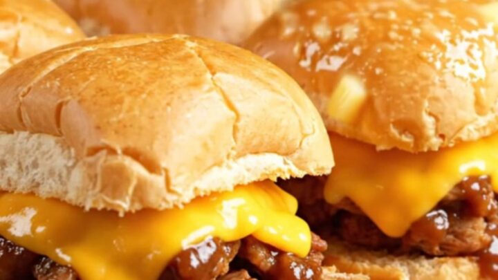 A close-up shot of Dr. Pepper and chipotle BBQ pulled pork sliders on Hawaiian rolls with melted cheese.